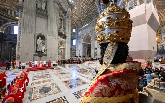 Bronze statue of St. Peter, adorned with Papal regalia, pictured from behind, Pallium Mass fills frame